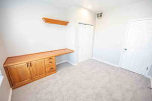 Unfurnished office with built in desk, light carpet, and recessed lighting