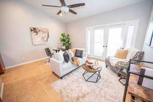 Living room featuring light tile patterned flooring, french doors, a ceiling fan, and vaulted ceiling