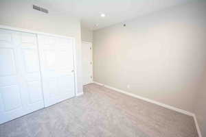 Unfurnished bedroom featuring light carpet and a closet
