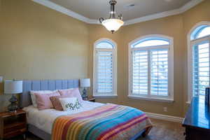 Bedroom with multiple windows, crown molding, and carpet flooring