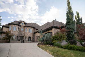 French provincial home featuring concrete driveway, a garage, a front yard, and brick siding