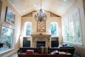 Living room featuring a glass covered fireplace, a chandelier, high vaulted ceiling, and plenty of natural light