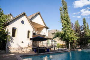Back of property featuring a balcony, a patio area, stucco siding, and a mountain view