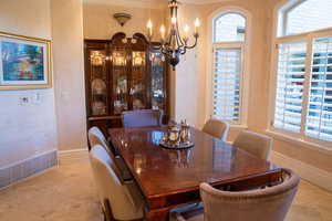 Dining space featuring a chandelier, a textured wall, and ornamental molding