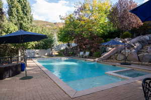 View of pool with a patio, a water slide, a fenced backyard, and a pool with connected hot tub