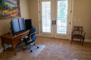 Carpeted home office featuring french doors and baseboards