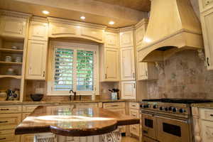Kitchen with range with two ovens, custom exhaust hood, dark stone countertops, open shelves, and recessed lighting