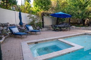 View of swimming pool featuring a patio area, a fenced backyard, and a pool with connected hot tub