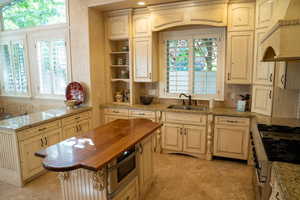 Kitchen with wooden counters, appliances with stainless steel finishes, premium range hood, a peninsula, and open shelves