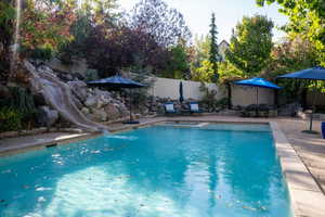 View of pool with a water slide, a fenced backyard, and a patio area