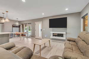 Living room with light wood-style flooring, recessed lighting, and a fireplace