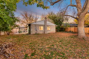 Rear view of house featuring a fenced backyard, a chimney, a patio, and brick siding