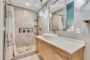 Full bath with tiled shower and vanity