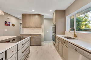 Kitchen featuring dishwashing machine, light stone counters, backsplash, recessed lighting, and hanging light fixtures