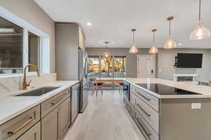 Kitchen featuring pendant lighting, gray cabinetry, light wood-style flooring, stainless steel appliances, and a kitchen island