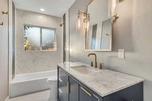 Bathroom with shower / bathtub combination, vanity, and light wood-type flooring
