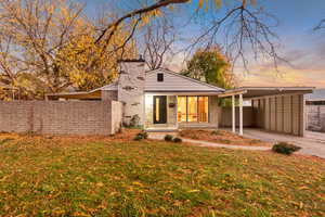View of front of home with a chimney, an attached carport, brick siding, and driveway