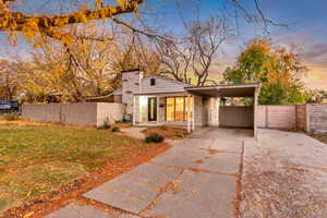 Mid-century modern home featuring a chimney, driveway, a carport, and brick siding