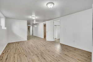 Finished below grade area featuring light wood-style flooring and a textured ceiling