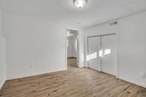 Unfurnished bedroom with light wood finished floors and a closet