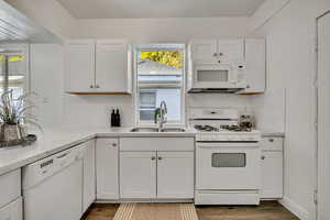 Kitchen featuring white appliances, white cabinetry, decorative backsplash, and light stone counters