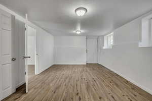 Basement featuring light wood-style flooring and a textured ceiling