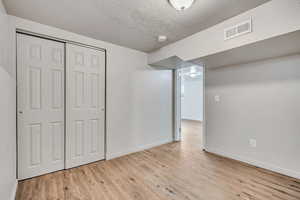 Unfurnished bedroom with light wood-type flooring, a textured ceiling, and a closet