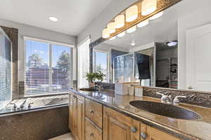 Bathroom featuring a shower stall, a walk in closet, double vanity, a garden tub, and recessed lighting
