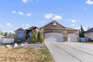 View of front facade with stone siding, a garage, driveway, and stucco siding