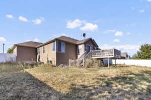 Back of property with a deck, stucco siding, and stairs