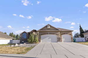 View of front of home featuring a garage, stucco siding, driveway, and stone siding