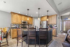 Kitchen featuring tasteful backsplash, arched walkways, a breakfast bar, stainless steel appliances, and pendant lighting