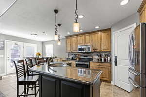 Kitchen featuring hanging light fixtures, appliances with stainless steel finishes, dark stone countertops, decorative backsplash, and recessed lighting
