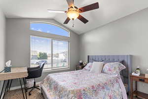 Bedroom with vaulted ceiling, a ceiling fan, and carpet floors