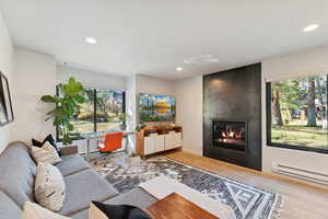 Living area with wood finished floors, a fireplace, an office area, recessed lighting, and a baseboard heating unit