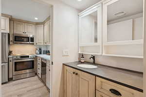 Kitchen featuring appliances with stainless steel finishes, backsplash, light wood-style flooring, light brown cabinets, and recessed lighting