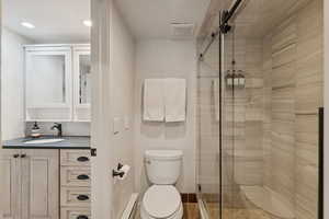 Bathroom with vanity, a stall shower, and a baseboard radiator