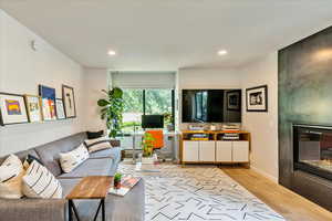 Living area with a large fireplace, wood finished floors, and recessed lighting