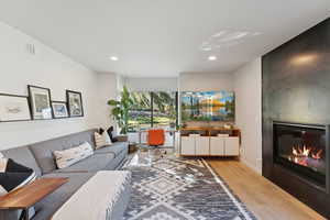 Living room with light wood-style flooring, a large fireplace, and recessed lighting
