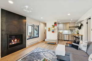 Living area with light wood-type flooring, baseboard heating, recessed lighting, and a fireplace