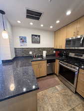 Kitchen featuring appliances with stainless steel finishes, pendant lighting, recessed lighting, backsplash, and a peninsula