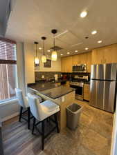 Kitchen featuring stainless steel appliances, a peninsula, a textured ceiling, decorative light fixtures, and a kitchen breakfast bar