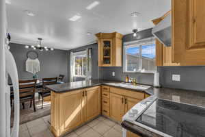 Kitchen with electric cooktop, light tile patterned flooring, a peninsula, glass insert cabinets, and recessed lighting
