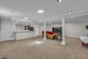 Living area featuring light colored carpet, ornamental molding, and wood walls