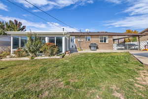 View of front facade featuring brick siding, a front yard, a sunroom, a carport, and entry steps
