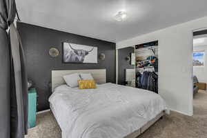 Bedroom with carpet floors, wallpapered walls, a closet, and an accent wall