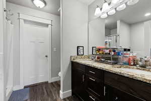 Full bathroom featuring double vanity, dark wood-style flooring, a shower with curtain, and a textured ceiling
