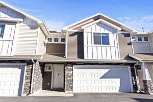 Craftsman inspired home with board and batten siding, stone siding, roof with shingles, a garage, and driveway