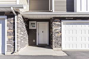Entrance to property featuring stone siding and an attached garage