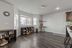 Dining area with a textured ceiling and dark wood-style flooring